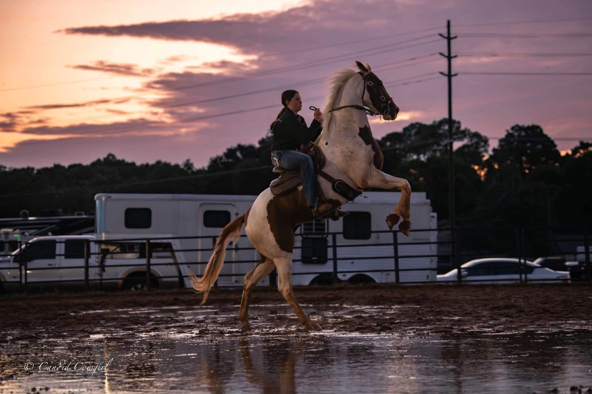 Emma on her paint horse rearing in a rain puddle at sunset